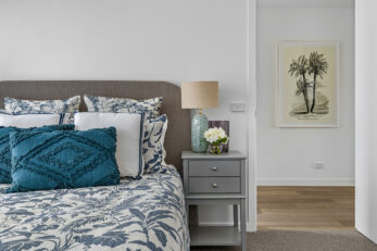 View of bed and beside table and doorway with picture hanging on wall in the hall area