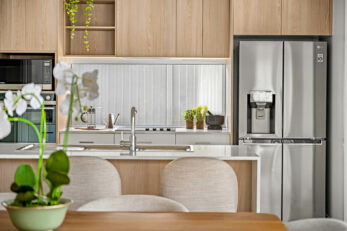 View of kitchen from lounge showing island with a sink, a fridge and a window